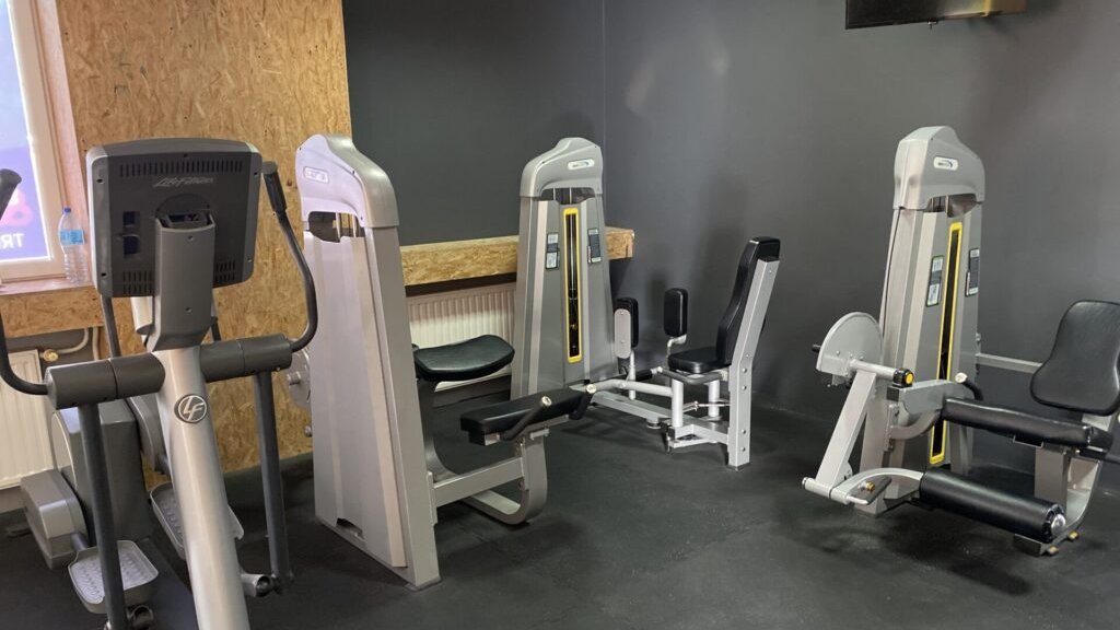 Wiele maszyn służących do treningu nóg oraz cardio znajdujących się na siłowni Fit family